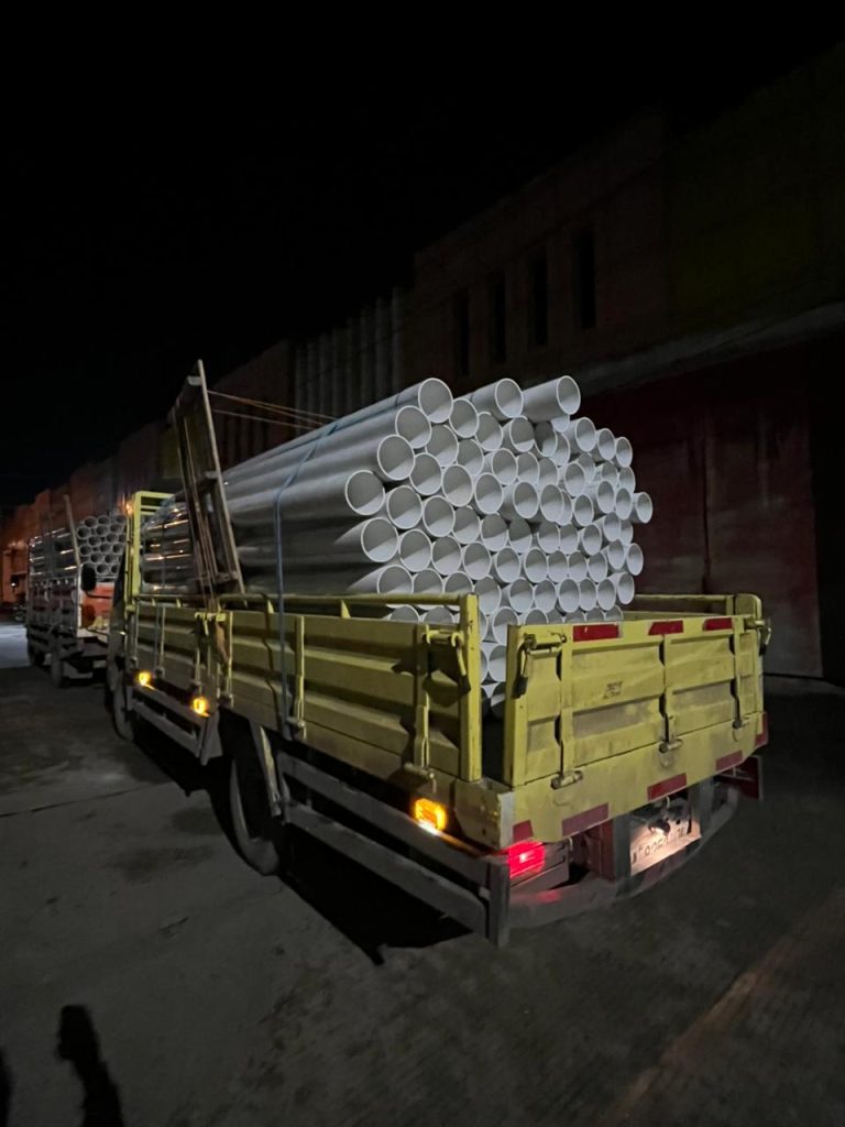 Armada truk distributor pipa proyek Kalimantan dari CV Pualam Pratama bersiap mengirim pasokan pipa uPVC kebun sawit di malam hari.