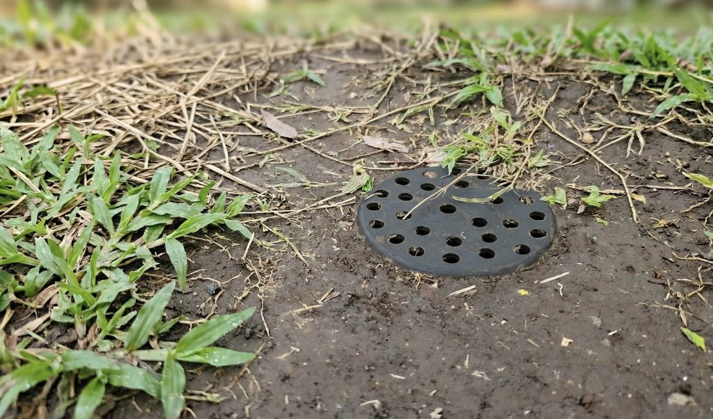 Penampakan Dop Tutup Lubang Biopori Pipa PVC Hitam yang Sudah Berlubang dan Terpasang Rata dengan Permukaan Tanah di Taman
